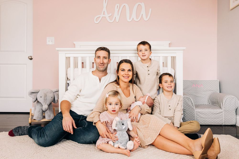 Family lounging together in a bright pink and white nursery.