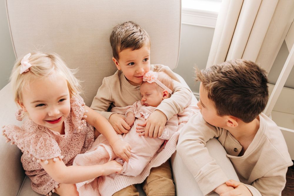 Siblings sharing tender moments together on light colored furniture.