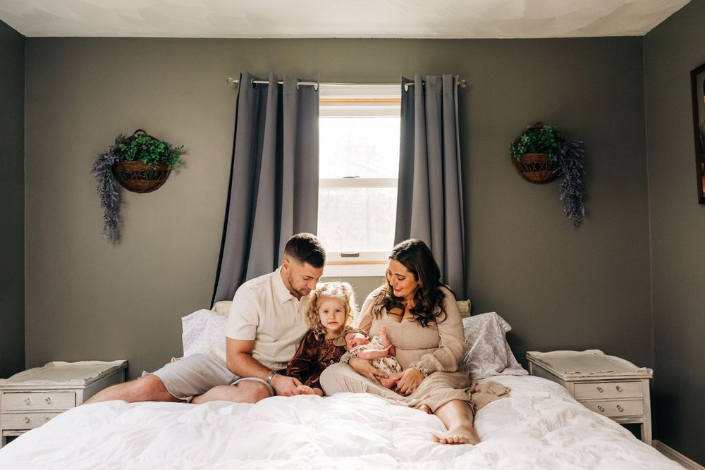 Lifestyle family photography session on white bed in modern gray bedroom.