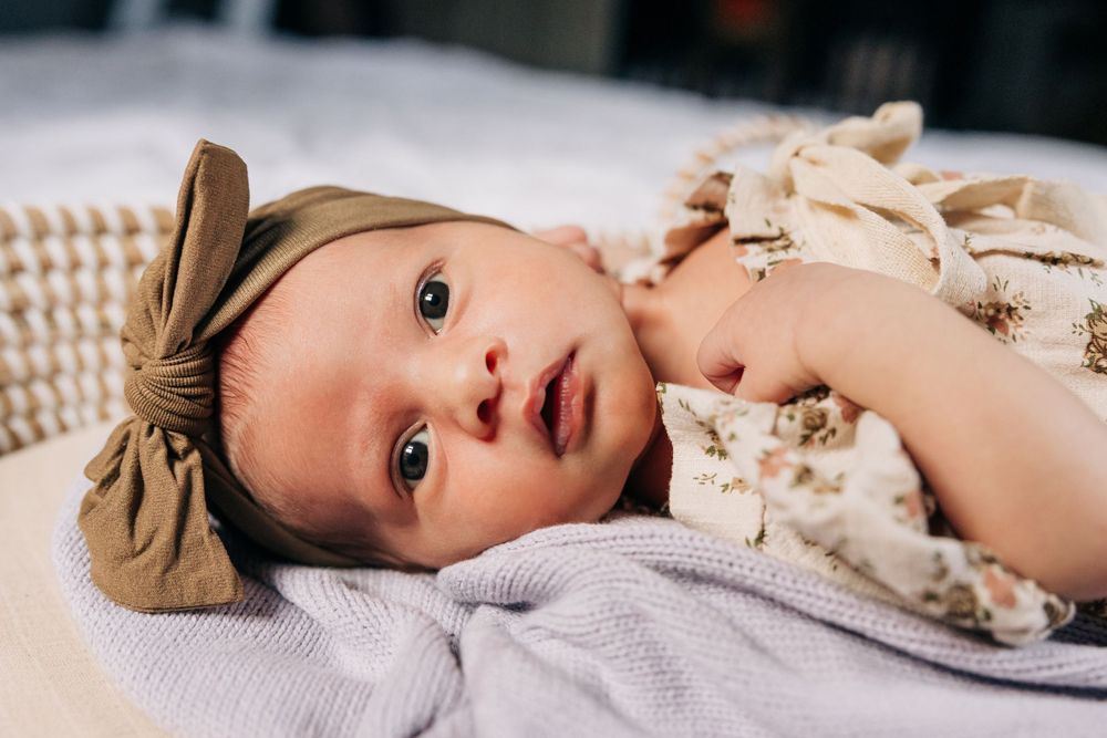 Artistic portrait of child lying on white bedding in soft natural light.