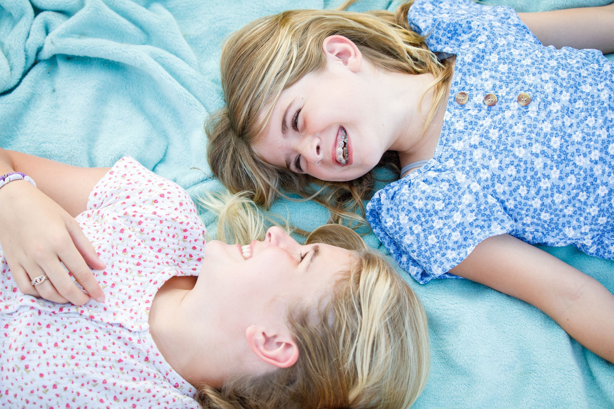A young child lies on a blue blanket while laughing and playing.