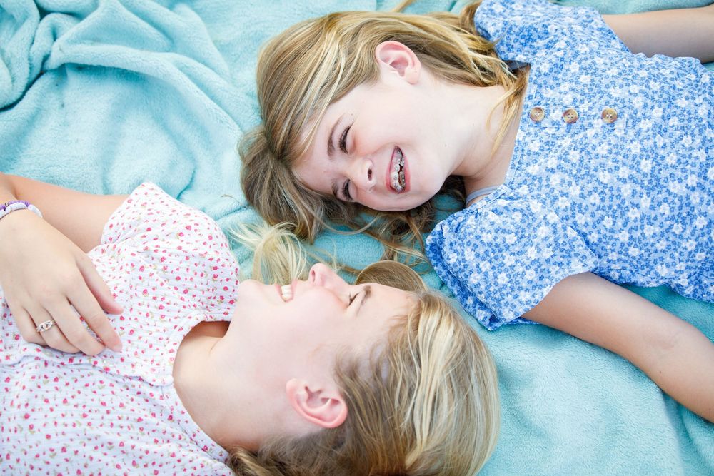 A young child lies on a blue blanket while laughing and playing.