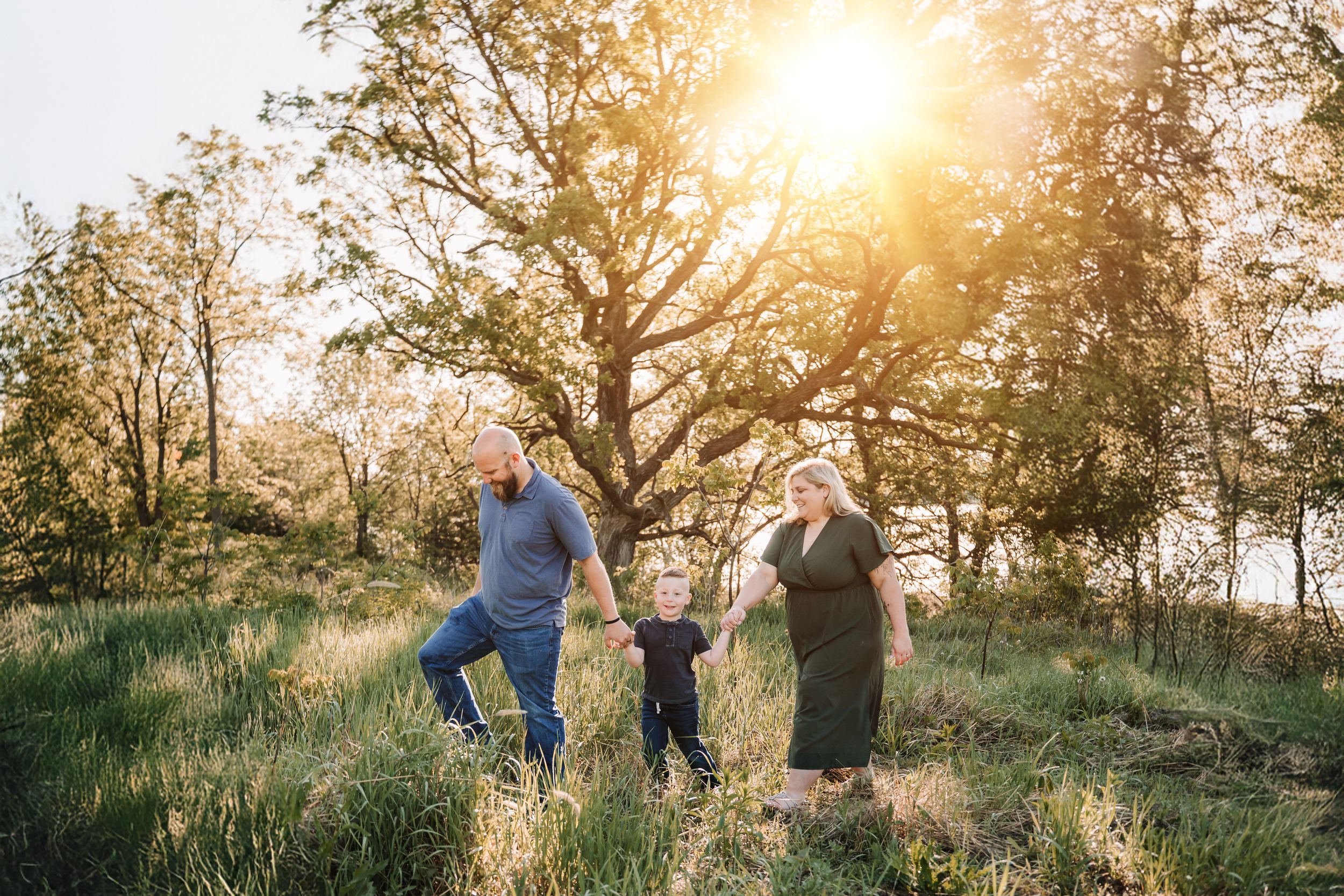 A couple enjoys a romantic golden hour moment walking together through a sunlit meadow at sunset.