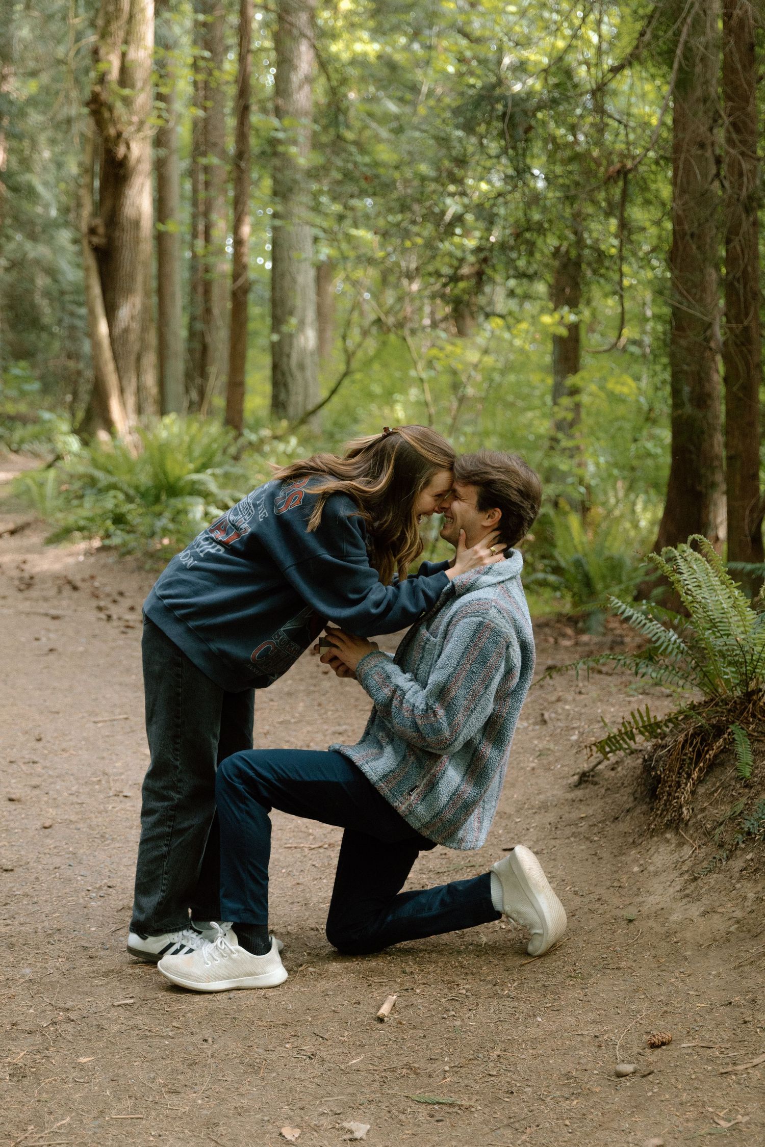 A sequence of four casual dance poses shown on a forest trail surrounded by green trees and ferns.