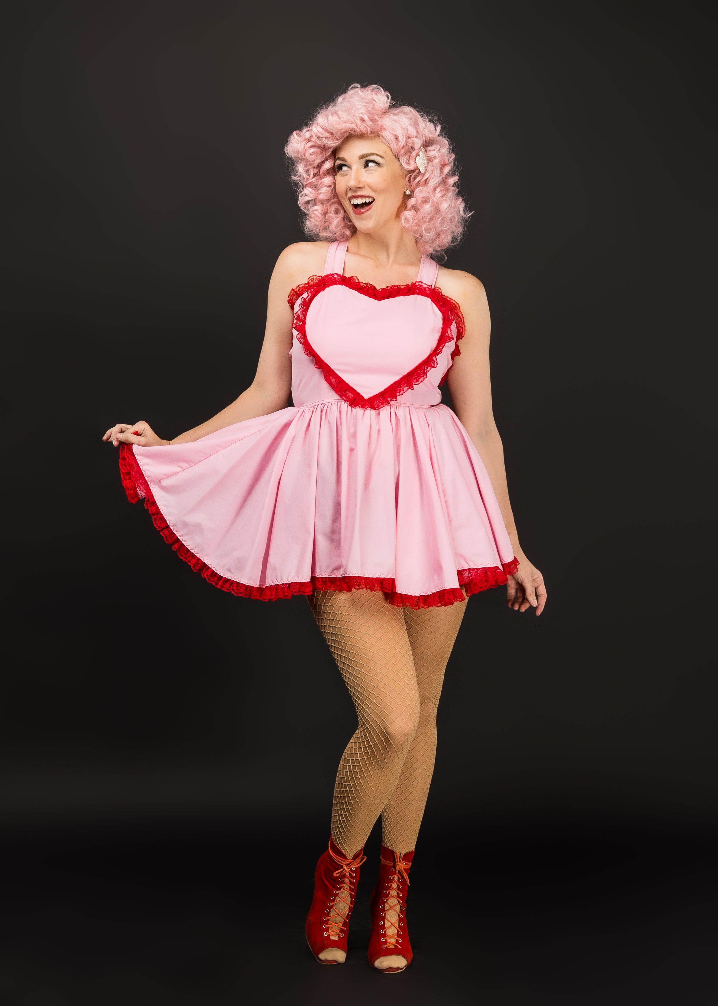 Playful retro-style poses in pink baby doll dress with red trim and fishnet stockings.