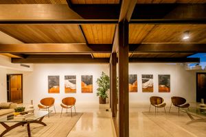 Modern basement lounge area with exposed wooden beams, white walls, and contemporary furniture in warm lighting.