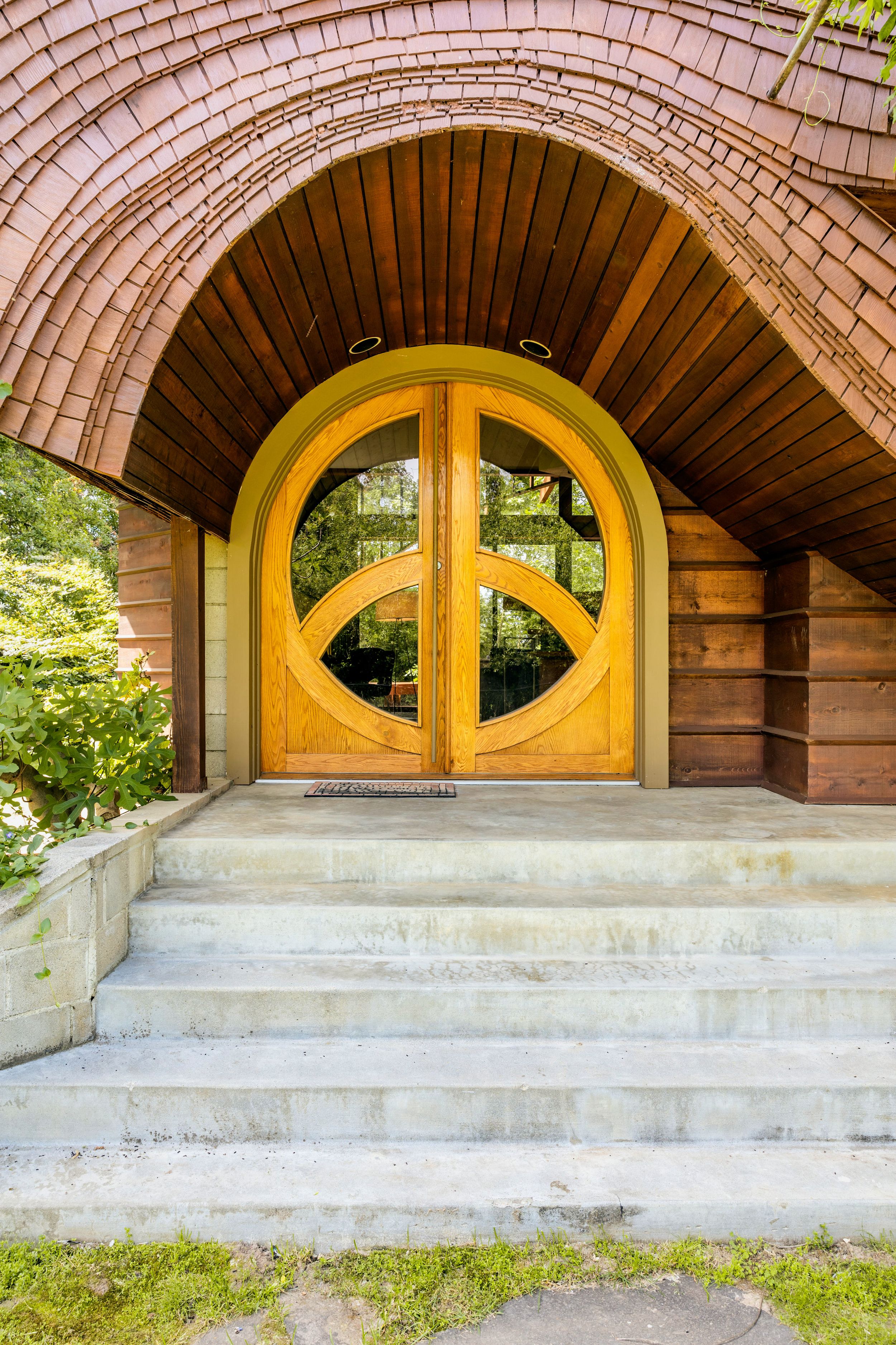 Architectural detail showing a series of curved wooden doorways with yellow arches against brick walls and concrete steps.