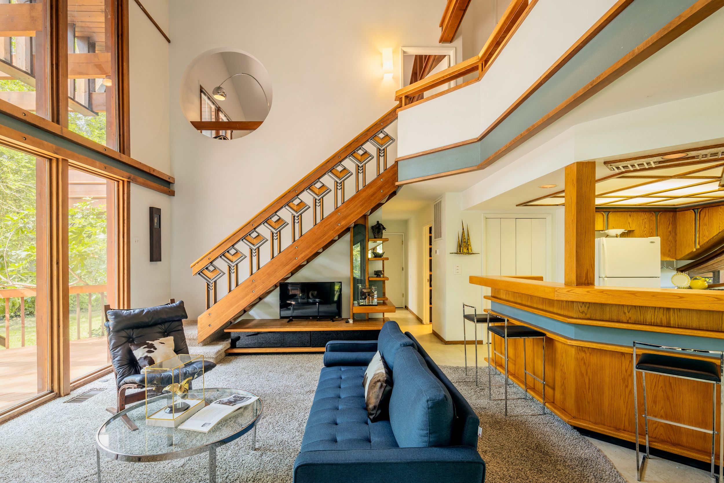Modern staircase with wooden railings and steps leads up to a bright landing area with large windows.