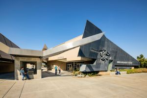 Contemporary museum entrance with dramatic angular roof design and sculptural elements.