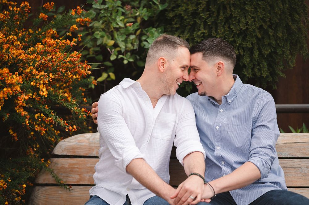 A romantic engagement photo with couple sitting on a bench surrounded by spring foliage in Manhattan, New York City.