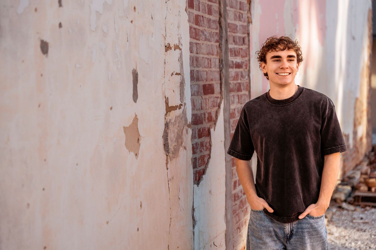 A person in a black t-shirt poses against a brick wall in a series of candid shots.