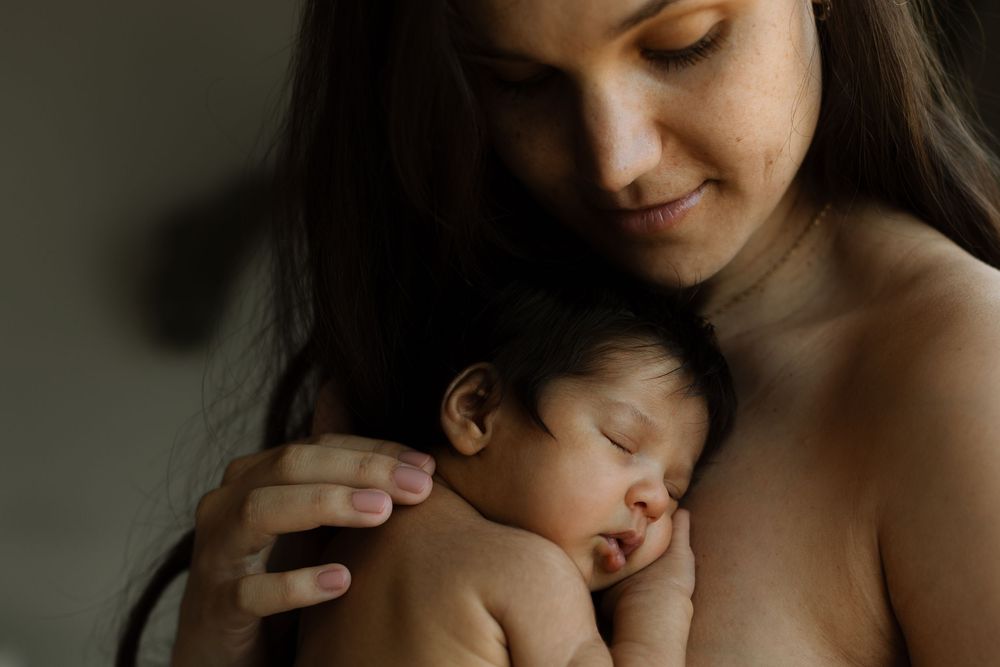 nyfødt baby som ligger inntil brystet til sin mamma