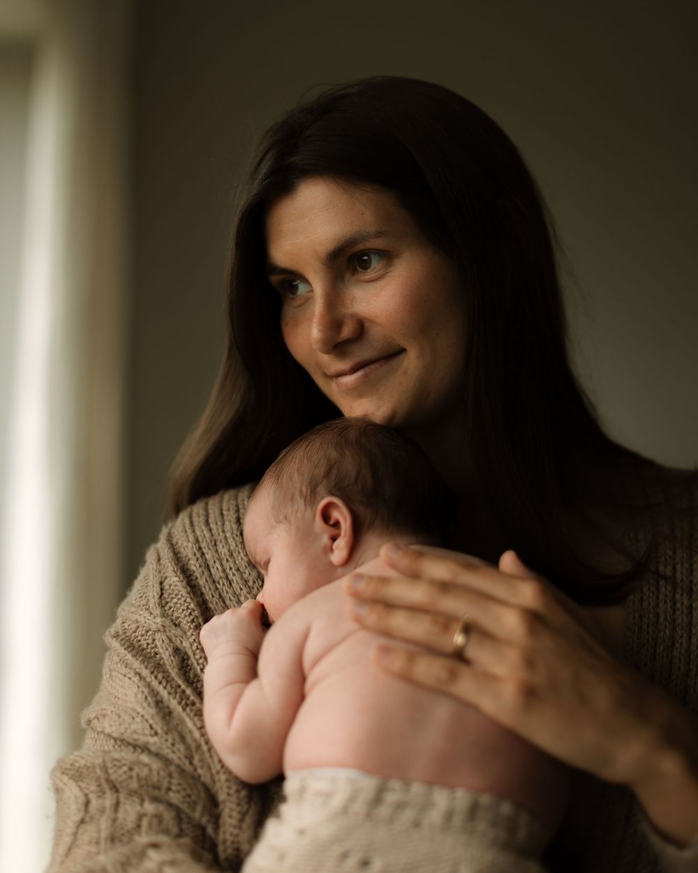 nyfødtfotografering i kristiansand mamma som holder sitt nyfødte barn inntil seg