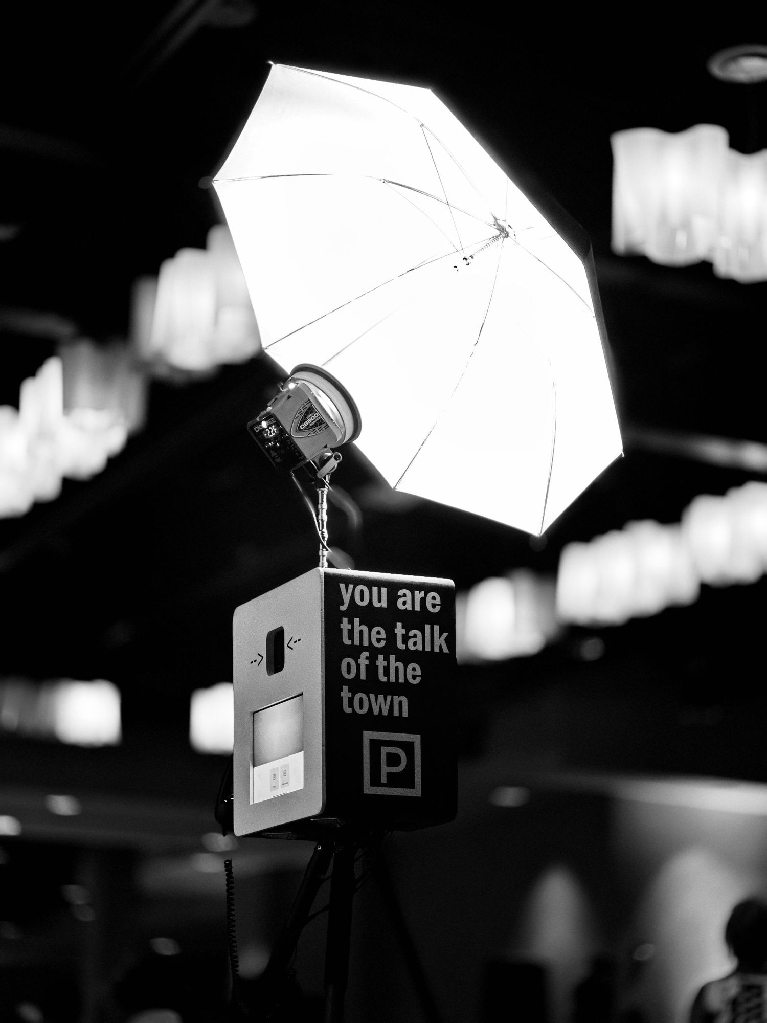 Photo Booth. With a set of umbrella silhouettes against a dark sky with street signs and urban lighting creating a moody atmosphere.
