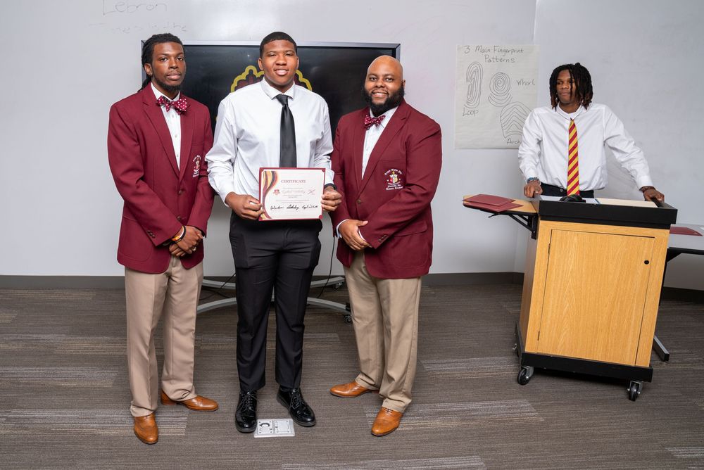 Students in maroon blazers and khaki pants pose with awards and certificates during a recognition ceremony.