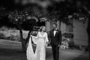 A couple takes a romantic stroll through a garden setting in formal wedding attire.