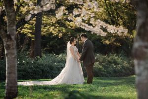 A couple shares a romantic moment in a sunlit garden setting surrounded by trees and lush greenery.