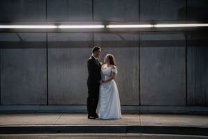 A couple sits together in a dimly lit concrete space creating a moody, atmospheric scene.