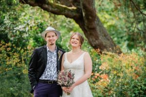 A couple celebrates their outdoor wedding in a lush garden setting with blooming flowers and trees.