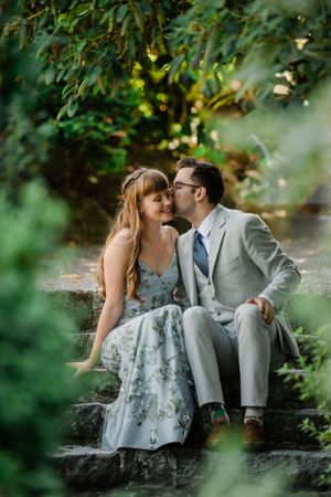 Intimate moment captured on stone steps surrounded by green foliage.
