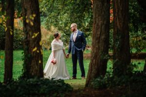 Two people share a moment in a wooded area with autumn colors.