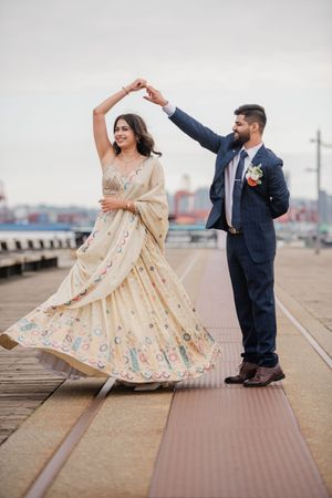 A couple dancing on wooden boardwalk boards as light floral dress twirls gracefully against urban backdrop.