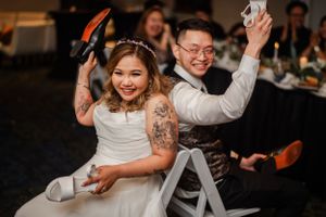 Playful wedding reception moment with couple holding up shoes during game activities.