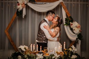 Romantic wedding ceremony setup with wooden arch, candles, and floral decorations.