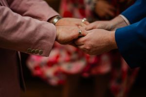 Close-up of hands exchanging rings during an intimate ceremony.