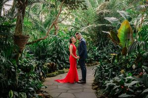 A couple shares a romantic moment in a lush botanical garden setting with vibrant greenery.