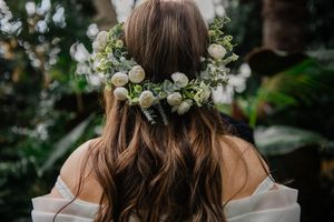 A delicate bridal hairstyle adorned with small white flowers and wispy strands captured from behind.