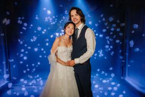 A couple shares a romantic dance under blue lighting and sparkles at their wedding reception.