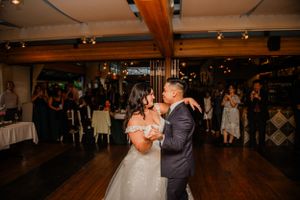 A tender first dance moment captured at an indoor wedding reception with wooden beams.