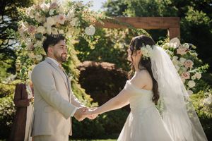 A romantic garden wedding ceremony with beautiful floral arrangements and sunlit greenery in the background.