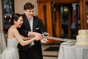 A bride and groom cut their wedding cake together during their reception celebration.