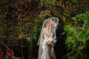 A couple shares an intimate moment in a lush garden setting during their wedding photoshoot.