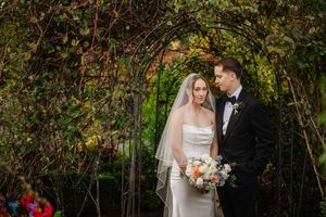 Romantic outdoor wedding ceremony with couple exchanging vows under lush green foliage.
