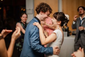 Dancing couple embraces during romantic first dance at indoor wedding reception.
