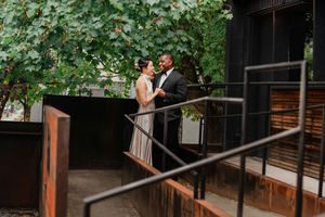 A couple shares a romantic moment on a rustic wooden deck surrounded by lush green foliage.