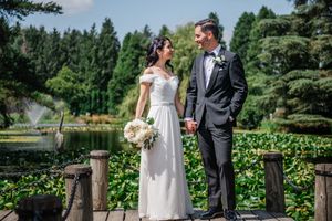 A couple shares an intimate moment during their lakeside wedding ceremony surrounded by evergreen trees and lily pads.