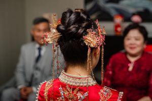 Ornate gold hair accessories and traditional Chinese bridal headpiece shown from behind against blurred background.