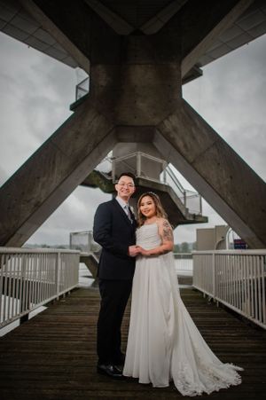 Wedding couple poses under geometric concrete architecture with dramatic lighting.