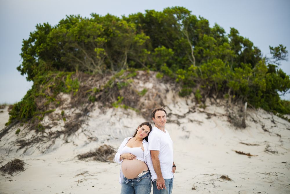 A couple strolls along a scenic sandy beach path surrounded by sea oats and natural dunes.