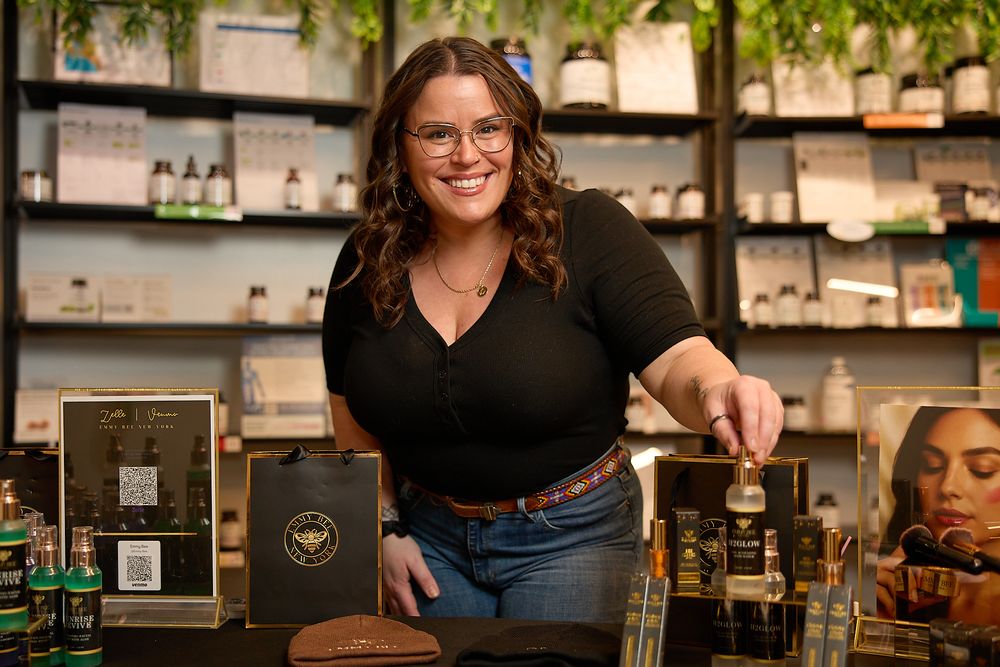 Barista working behind counter at specialty coffee shop with shelves of coffee equipment and supplies in background.