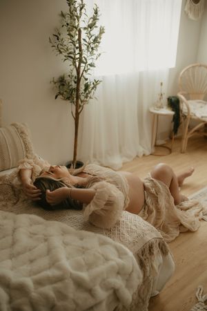 Ethereal boudoir photoshoot featuring soft white fabric and natural lighting in a minimalist indoor setting.