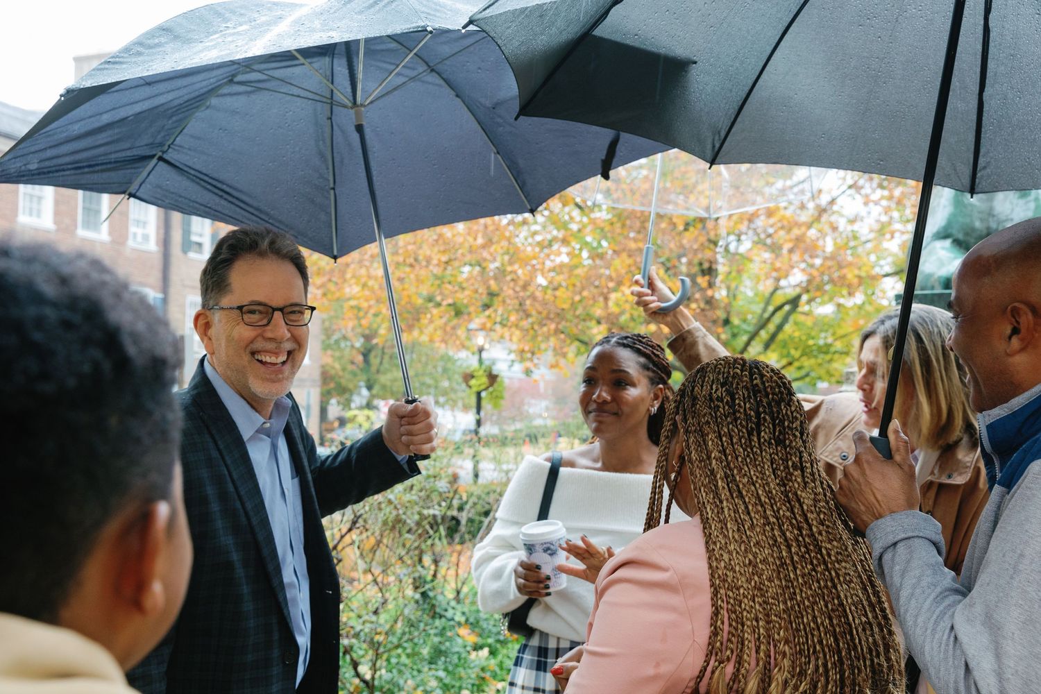 A group stands together under umbrellas during a rainy outdoor gathering or event.