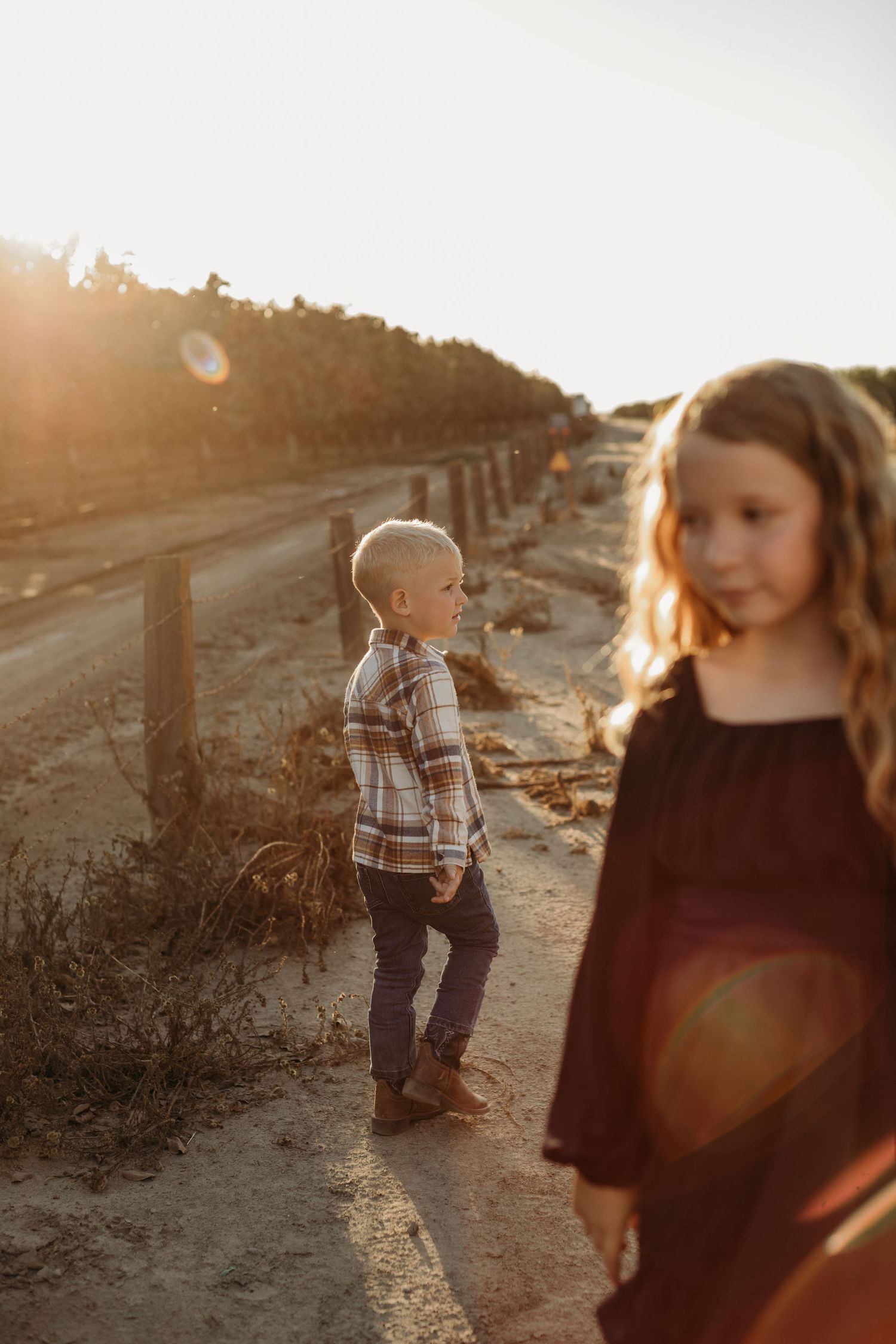 Children playing on a path at sunset with golden light and lens flare.
