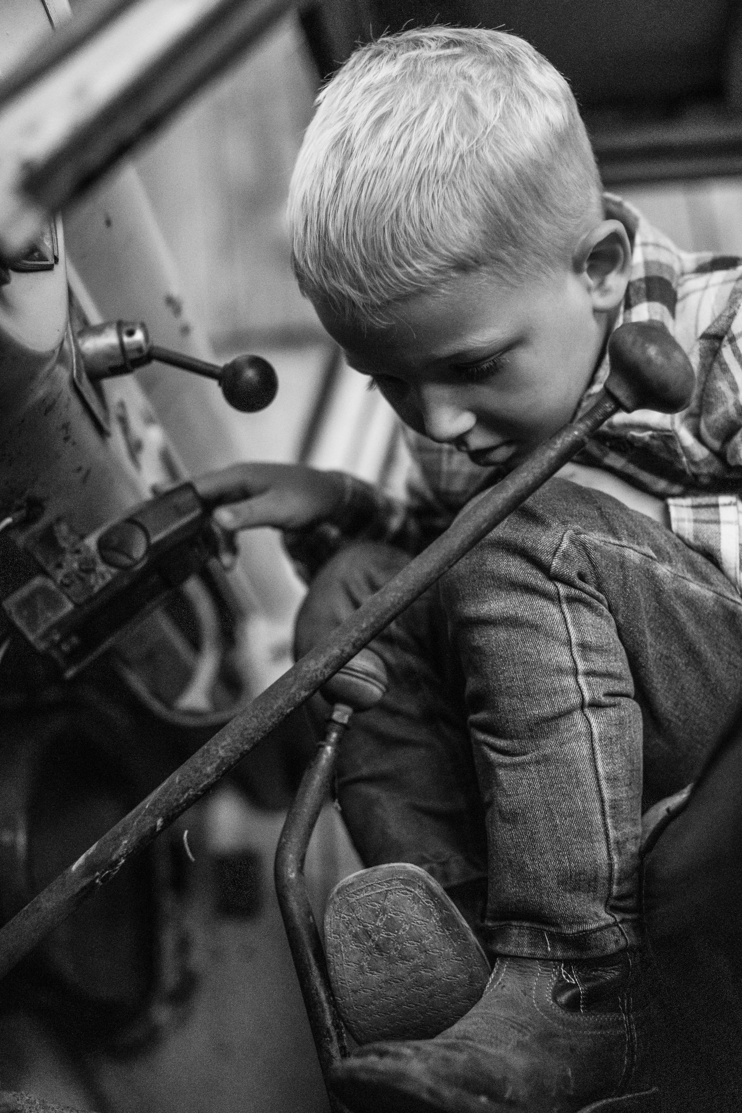Black and white portrait of child exploring vintage truck controls.