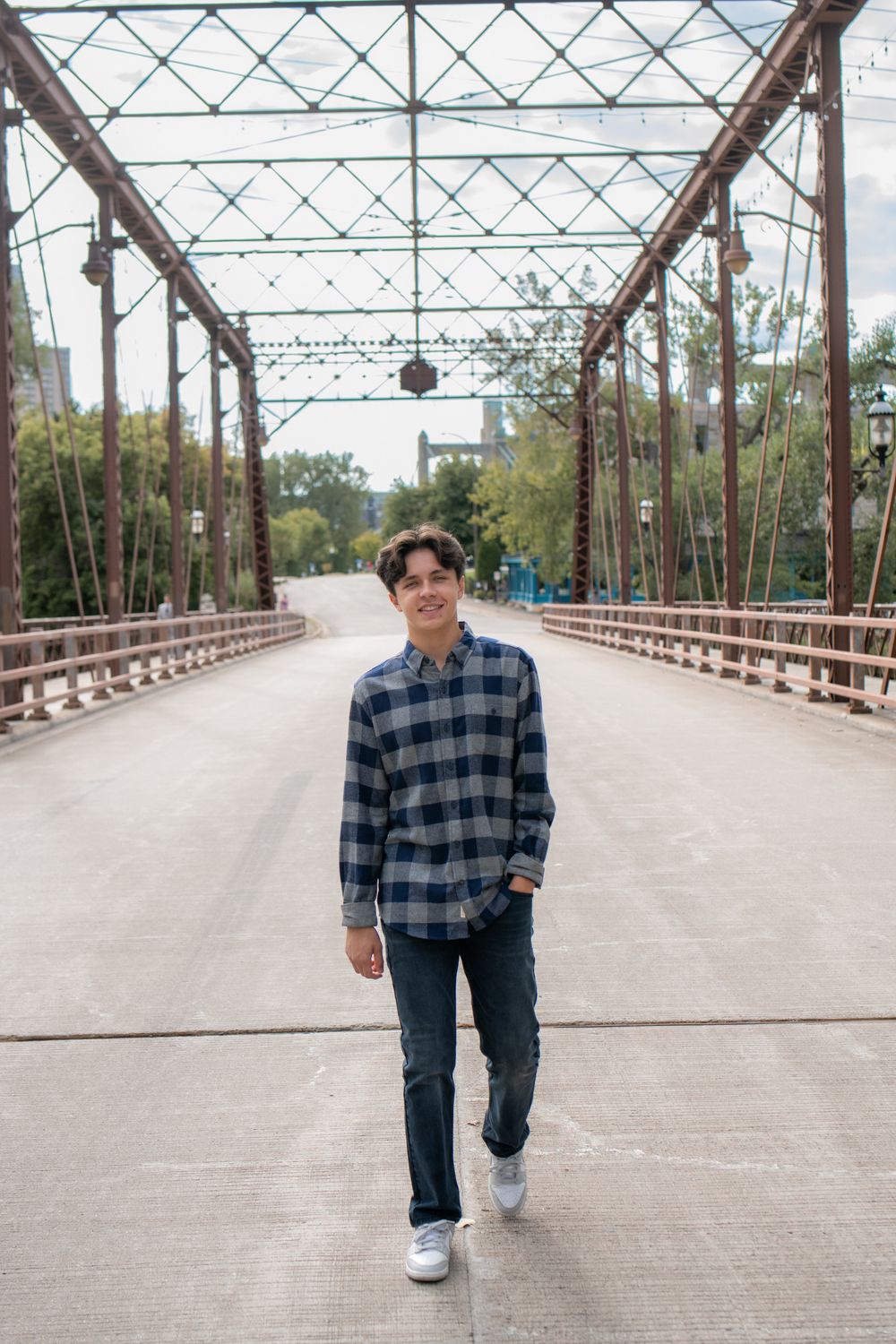 Person walking on a rustic metal truss bridge with wooden planks on a sunny day.