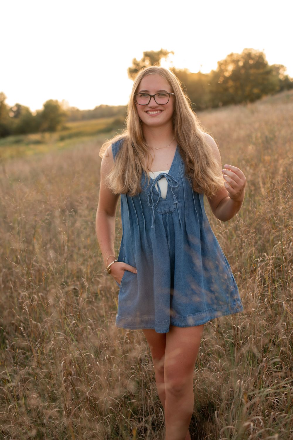 A series of outdoor portraits showing someone in a denim dress standing in a golden sunlit field at sunset.